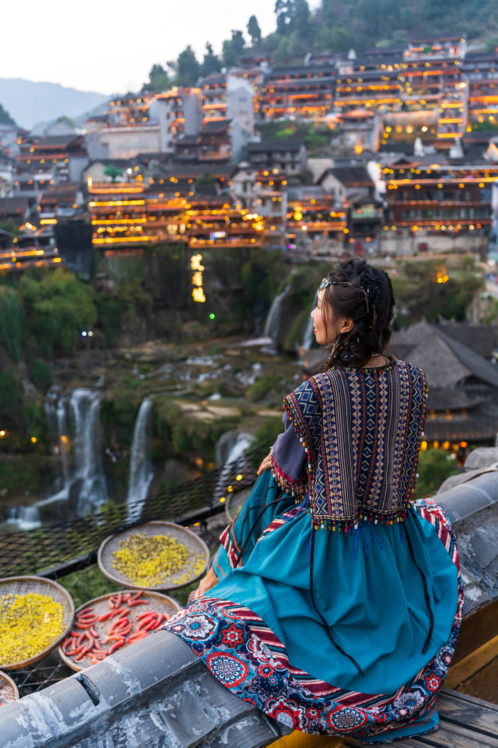 Mujer viendo una cascada desde las alturas en la ciudad de Lijiang